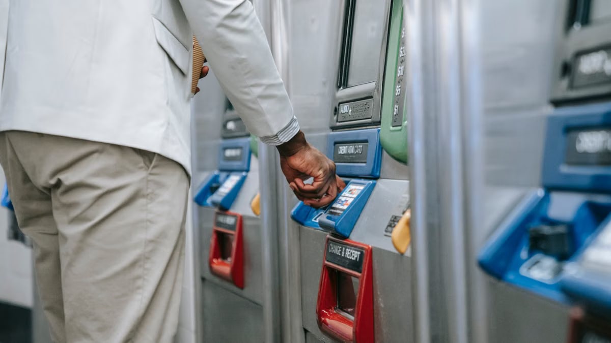 Close-up of a man purchasing a ticket using a modern subway machine.